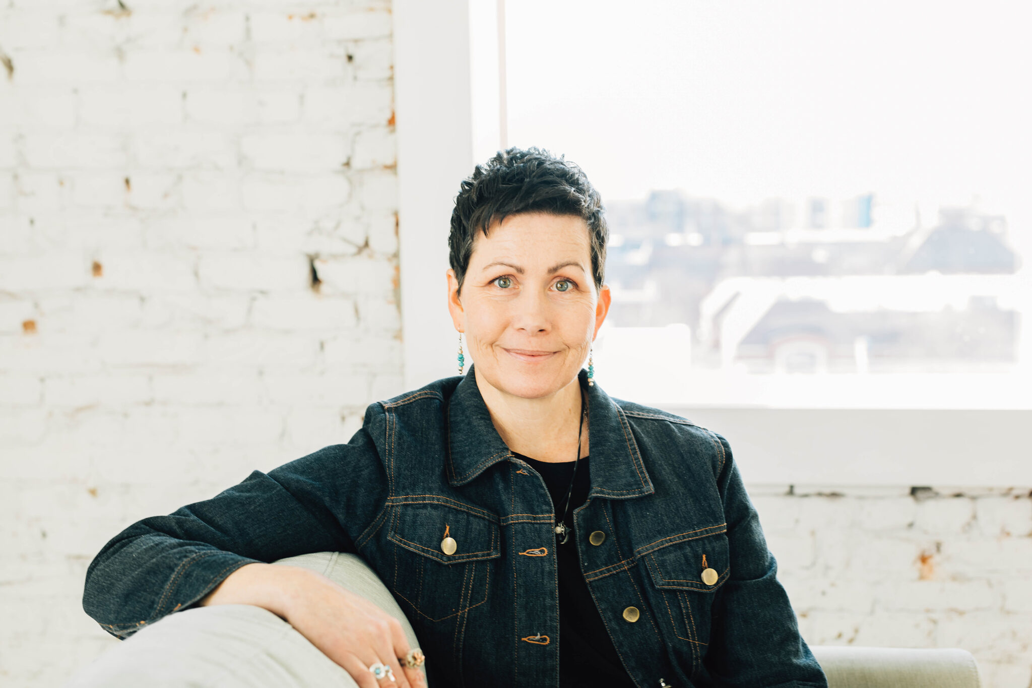 The author sitting on a sofa with one elbow over the back, smiling calmly at the camera